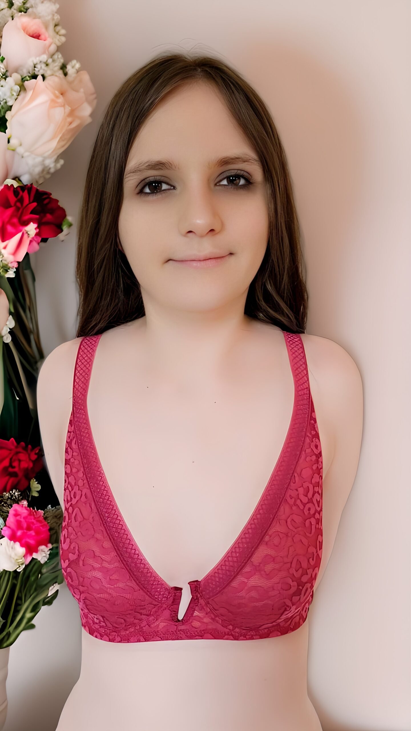 Femme portant un haut de soutien-gorge rose, souriante, avec un fond neutre.